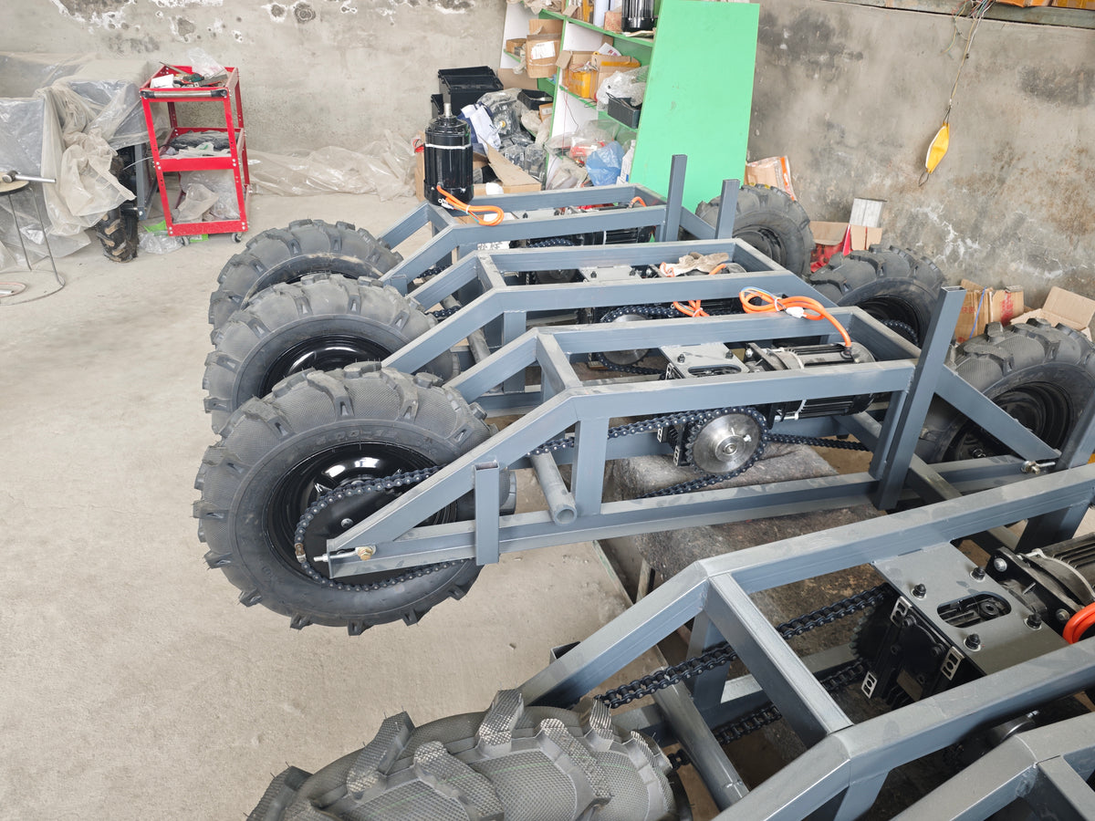 Supplier workshop photograph of transporter chassis showing steel frame members, wheels, motors and chains